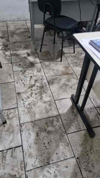 Piso de um ambiente interno mostrando marcas de lama e sujeira, indicando danos causados por alagamento.