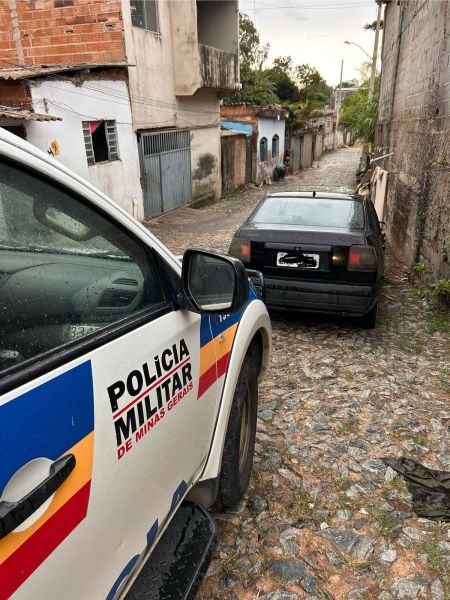 Veículo recuperado pela Polícia Militar em uma rua de Divinópolis, com uma viatura ao lado.