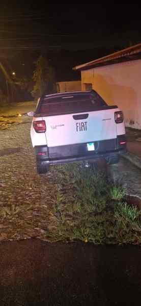 Caminhonete Fiat Strada Volcano estacionada em área suspeita à noite, com grama ao redor.