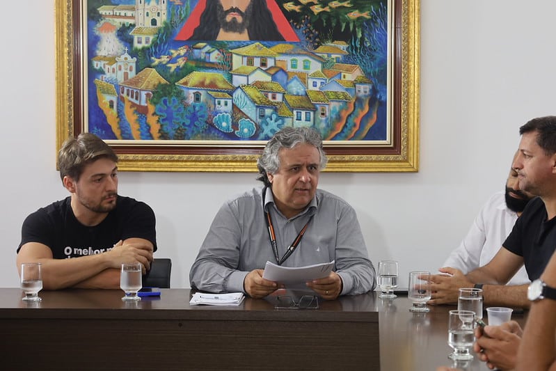 Reunião na Câmara Municipal de Divinópolis com membros do COMTUR apresentando o Plano Municipal de Turismo para 2027-2031. Os participantes discutem estratégias de fomento ao turismo na cidade.