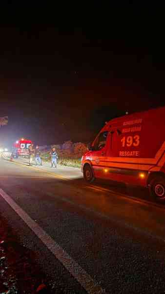 Emergency responders at night near a roadside with a rescue vehicle and flashing lights.