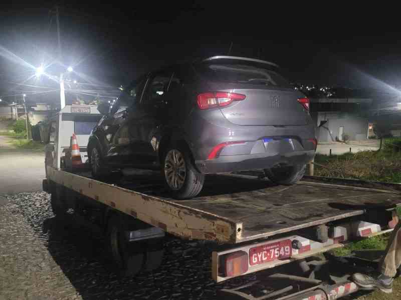 Veículo Argo sendo removido por uma equipe policial durante a noite, com luzes da cidade ao fundo.