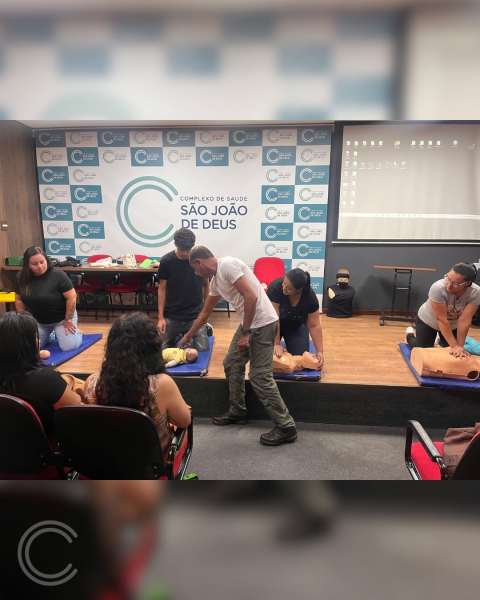 Aulão gratuito de primeiros socorros na Escola Técnica São João de Deus, com participantes aprendendo técnicas de ressuscitação em manequins.