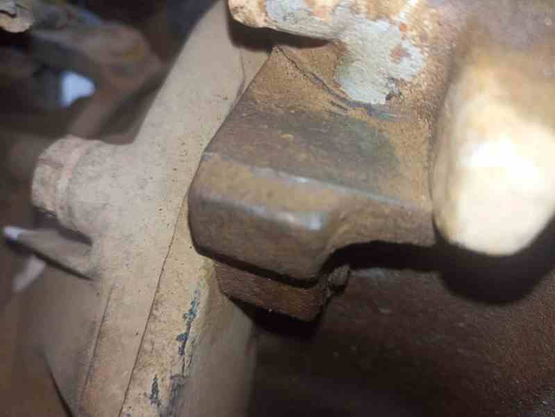 Close-up of a corroded and damaged vehicle part, highlighting signs of wear and potential modification.