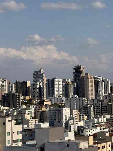 Vista panorâmica da cidade com prédios altos e composições urbanas, sob um céu parcialmente nublado.