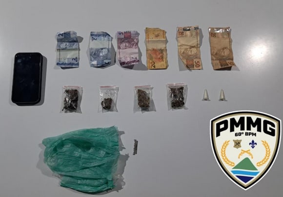 Apreensão de drogas, dinheiro e celular em operação da Polícia Militar de Minas Gerais, com destaque para porções de substâncias e notas em diferentes denominações.