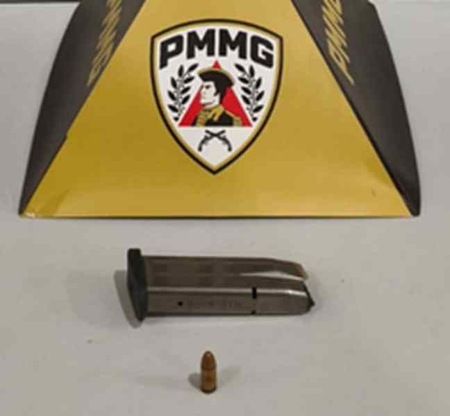 Imagem de uma urna de polícia militar, com um carregador de pistola e uma munição à frente, destacando a abordagem a crimes relacionados a armamentos.