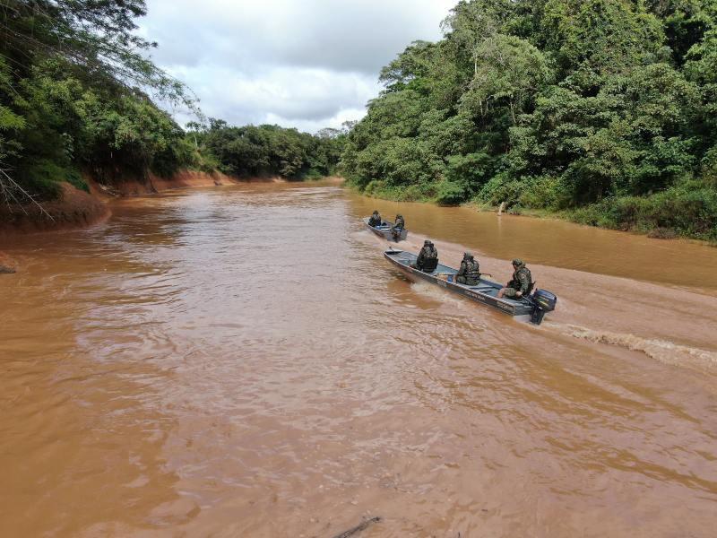 Embarcações patrulhando o rio com militares da Polícia Militar de Meio Ambiente realizando operações de fiscalização ambiental em uma área florestal.