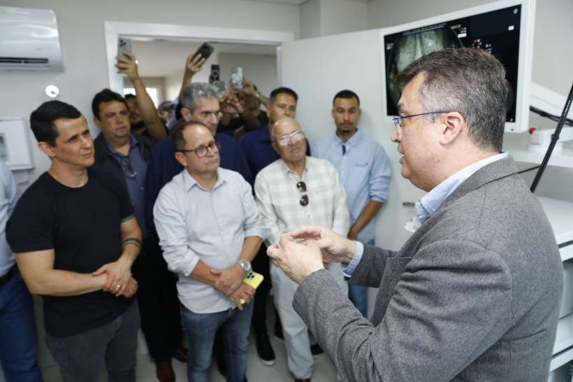 A inauguração do Serviço de Endoscopia e Colonoscopia em Divinópolis, com um especialista explicando para um grupo de pessoas sobre as novas tecnologias utilizadas.