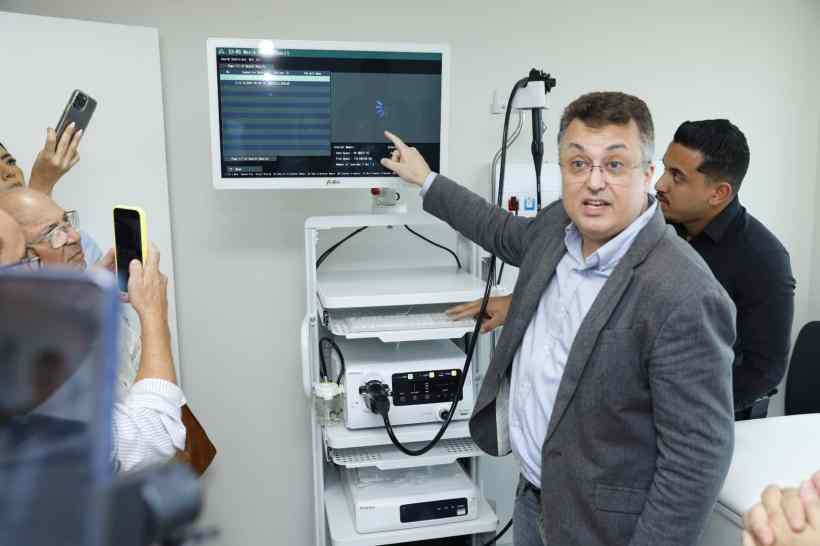 Médico apresentando equipamento de endoscopia em inauguração, com tela ao fundo exibindo dados.