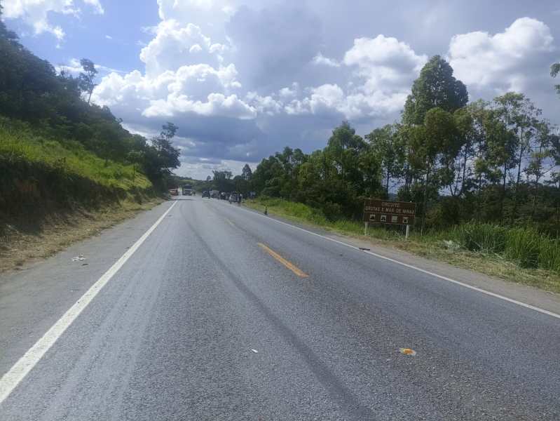 Estrada com sinalização, cercada por vegetação e céu nublado.