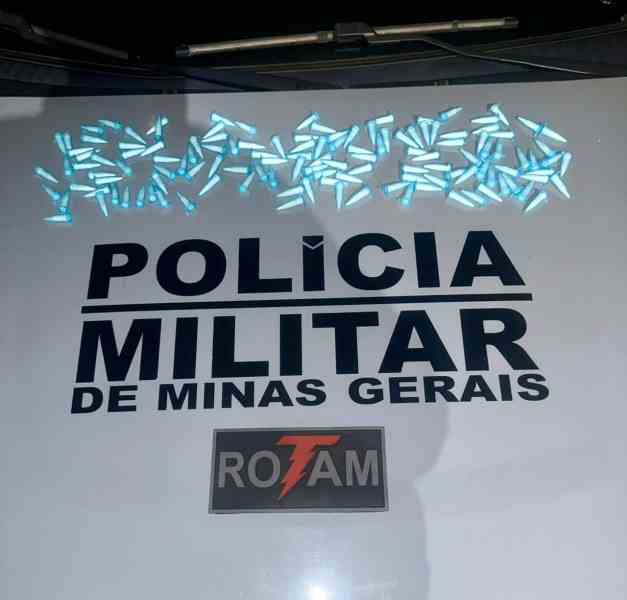Mesa com o logotipo da Polícia Militar de Minas Gerais e várias embalagens azuis dispostas sobre ela.