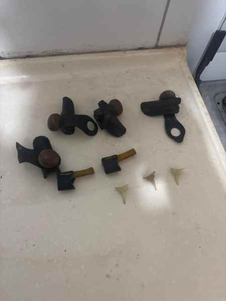 Conjunto de peças metálicas, incluindo alças e botões, sobre uma superfície clara.