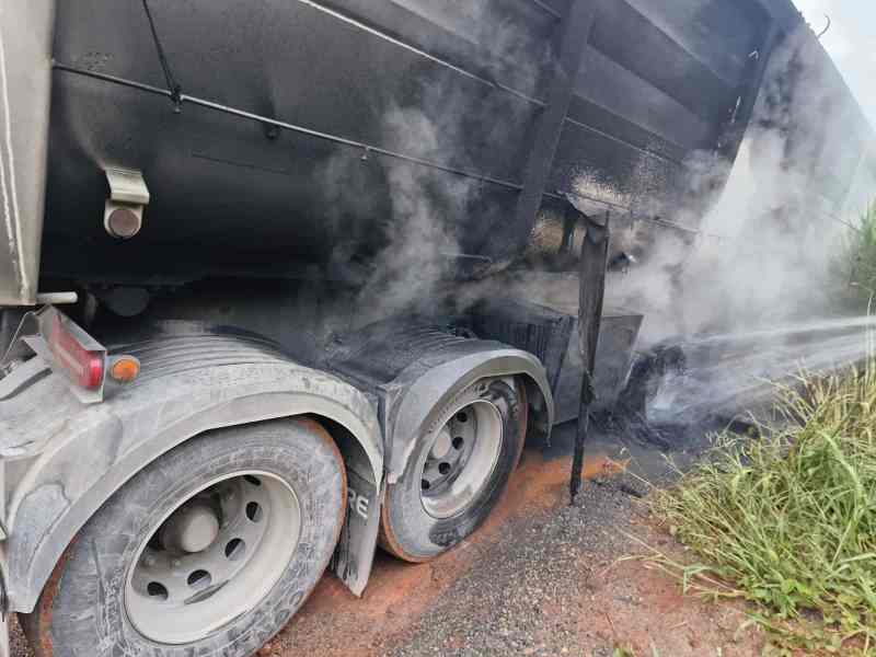 Caminhão basculante com fumaça e danos na parte traseira devido a um incêndio.