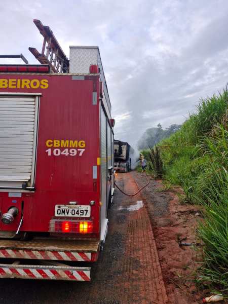 Caminhão de bombeiros em ação em uma estrada, com fumaça saindo de um veículo em chamas à frente.