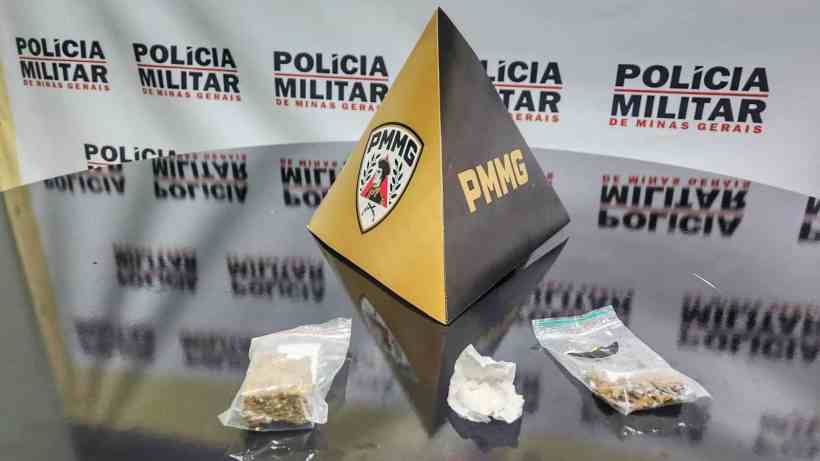 Uma pirâmide preta e dourada com o logo da Polícia Militar de Minas Gerais (PMMG) ao centro, com dois pacotes de substâncias em ambos os lados, um com uma substância branca e outro com uma substância marrom.