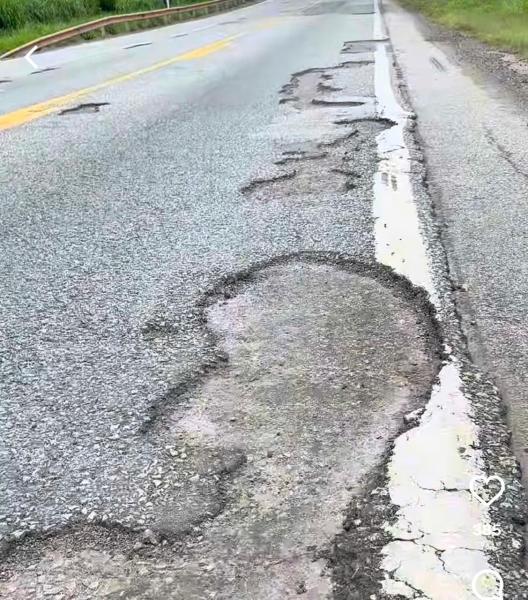 Trecho de estrada com asfalto danificado, mostrando buracos e irregularidades na superfície.