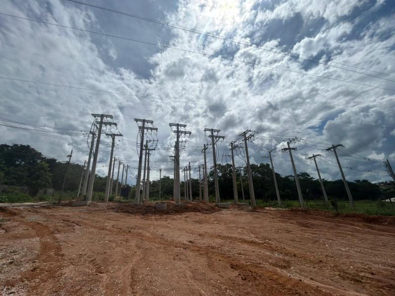 Estrutura de postes de energia elétrica em um terreno com céu nublado ao fundo.