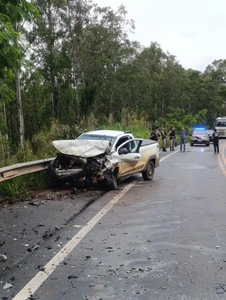 Veículo acidentado na beira da estrada, com a frente danificada e policiais realizando atendimento no local.