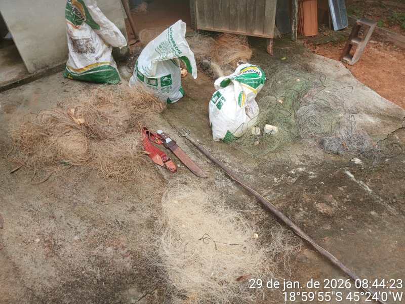 Diversas pilhas de fios e cordas sobre uma superfície de cimento, com sacos brancos e verdes ao fundo.