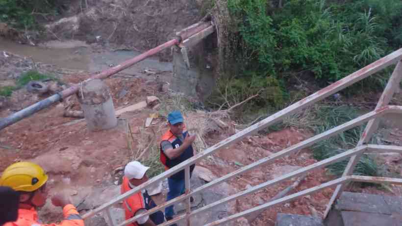 Grupo de trabalhadores em um local de construção, com um sistema de drenagem ao fundo e uma escada de metal visível.
