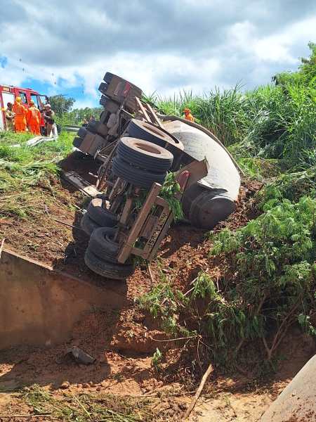 Caminhão virou em área ao lado de um barranco, com emergência e socorristas presentes.