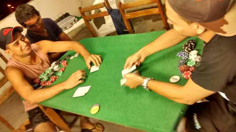 Three men playing poker at a green table with poker chips scattered around them.