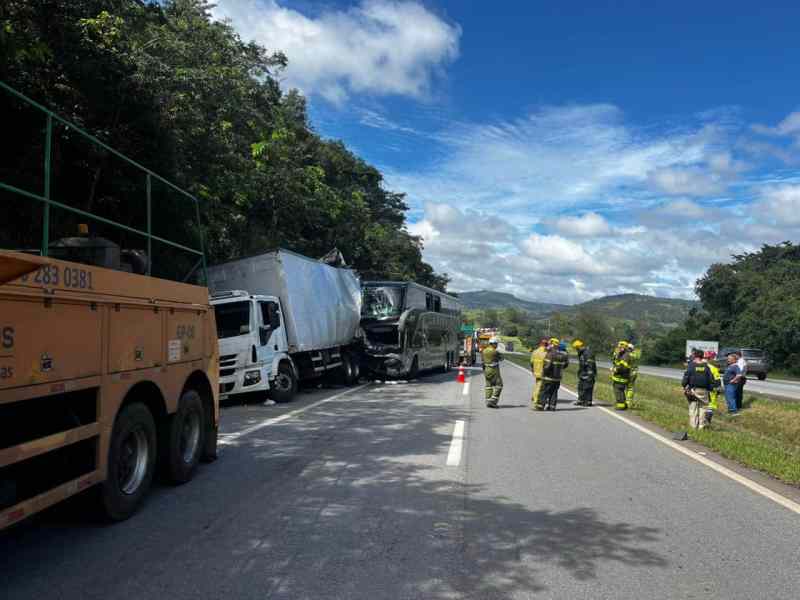 Acidente de trânsito com um caminhão e um ônibus na estrada, com equipes de resgate presentes.