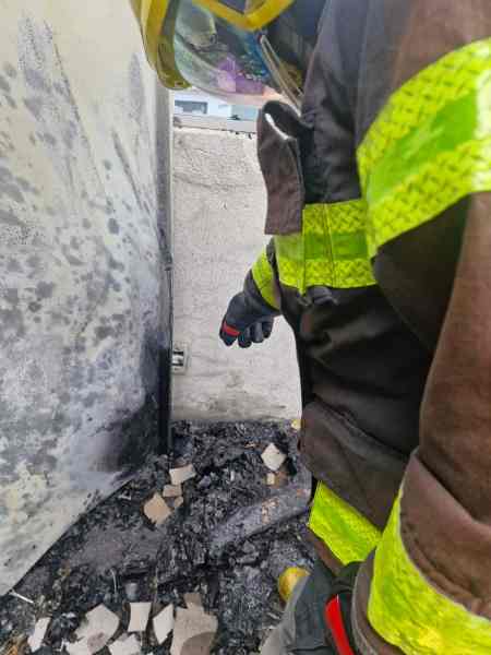 Bombeiro examinando áreas queimadas com detritos ao redor.