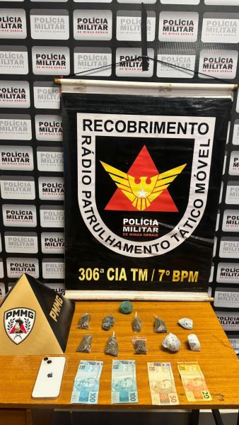 Imagem exibe materiais apreendidos pela Polícia Militar, incluindo uma placa com os emblemas da polícia, várias pedras, dinheiro em notas e um celular.