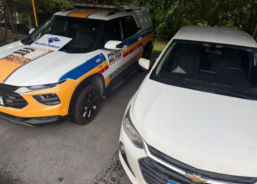 Foto de um carro da Polícia Militar Rodoviária ao lado de um carro de passeio branco estacionado.