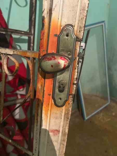 Fechadura de porta antiga com marcas de ferrugem e tinta descascada, em um ambiente interno.