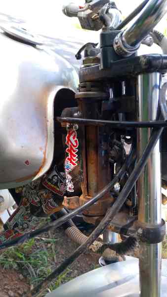 Detalhe de uma motocicleta mostrando o tanque, cabos e componentes do motor.