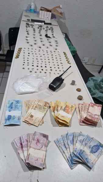 Mesa com diversos objetos, incluindo dinheiro em notas e moedas, uma substância branca não identificada, e um rádio comunicador.