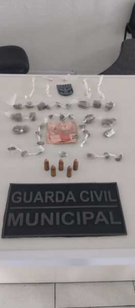 Materiais apreendidos pela Guarda Civil Municipal, incluindo embalagens de drogas, um maço de dinheiro e cartuchos.