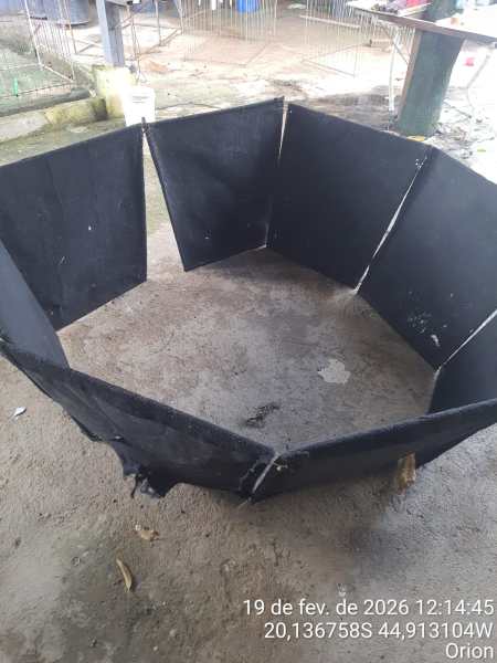 Estrutura hexagonal de proteção feita de material preto, montada em um piso de terra.