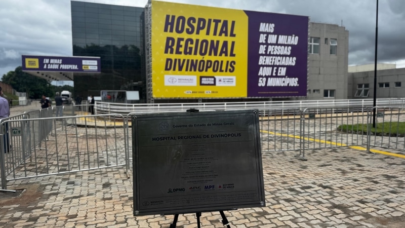 Fachada do Hospital Regional de Divinópolis com placa informativa e painel destacando o benefício para mais de um milhão de pessoas.